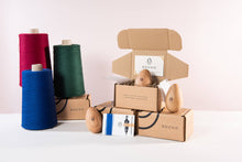 Load image into Gallery viewer, Socko mending egg. Product layout with mending yarns, needle threader, stacked packaging boxes.Wooden Darning egg. White background. Sustainable Haberdashery. Sewing tools. Swiss darning. Mending. Glasgow