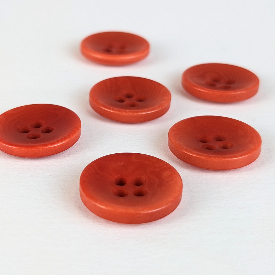 15mm four hole coral red corozo buttons on white background