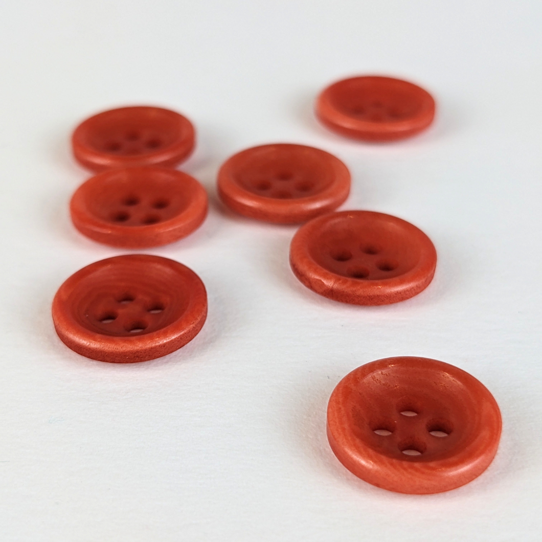 12mm four hole coral red corozo buttons on white background