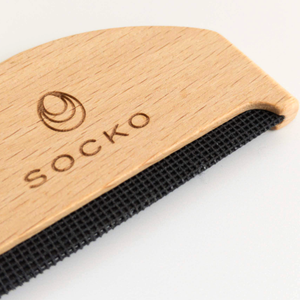 Close up of Socko Pilling comb for debobbling your knitwear. care for cashmere. clothing care. wooden handle clothing comb. white background flat lay.
