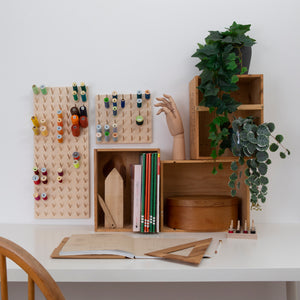 Range of birch ply peg boards on display and in use. Wall mounted at a desk with books, plants and haberdashery 