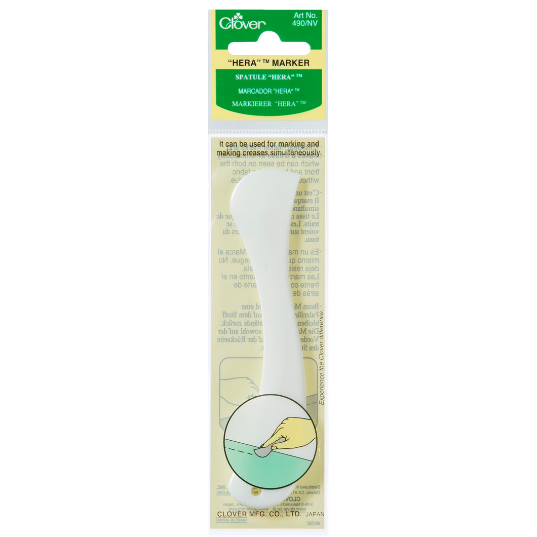Clover hera marker for creasing a mark into fabric for quilting. Small sharp rounded white plastic sewing tool in green clover branded plastic packaging. 