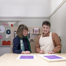 Load image into Gallery viewer, Location at Bawn Textiles, person on left is Becky of Ploterre. Person on Right is Bevan of Bawn Textiles, both looking at their collaborative artwork of limited edition riso print graphic. Glasgow City Council street mapping with jacquard weaving design. 
